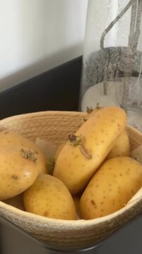 Raw potatoes in a basket beside a decorative vase