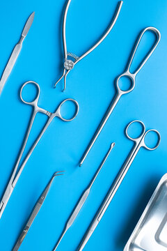 Pattern flat lay of stainless surgical instruments and tools on blue table, top view. Medical background