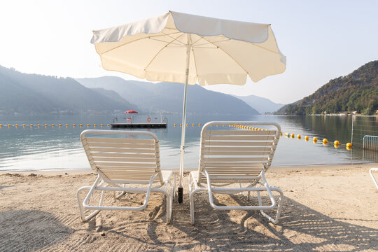 Two deckchairs on a small beach overlooking Lake Ceresio.