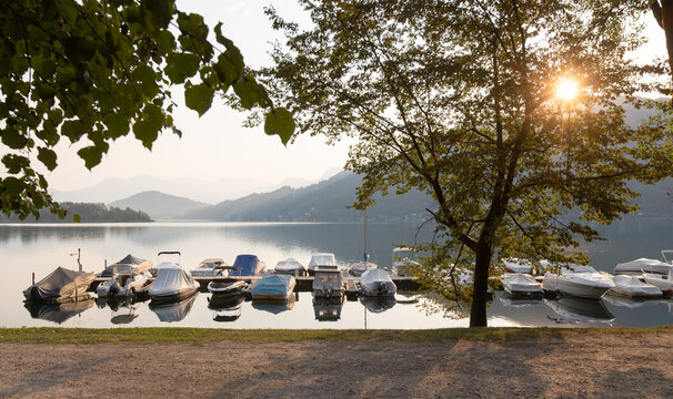 A small harbour with lake boats. A romantic scene in Caslano, Switzerland. Early morning with the sun behind the scene.