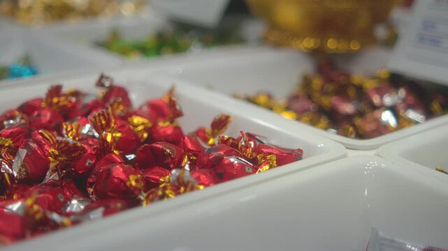 Assorted wrapped candies displayed in white trays at a confectionery or candy shop