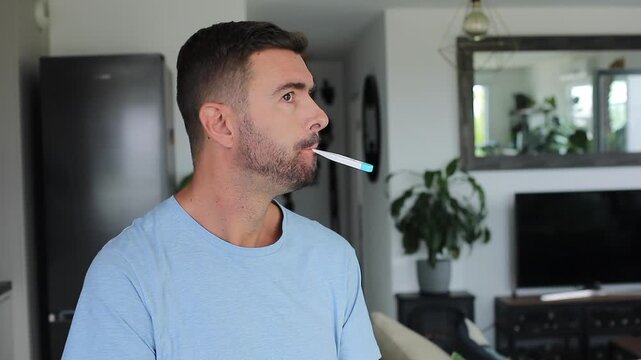 Sick man checking electronic mouth thermometer and reacting to high fever