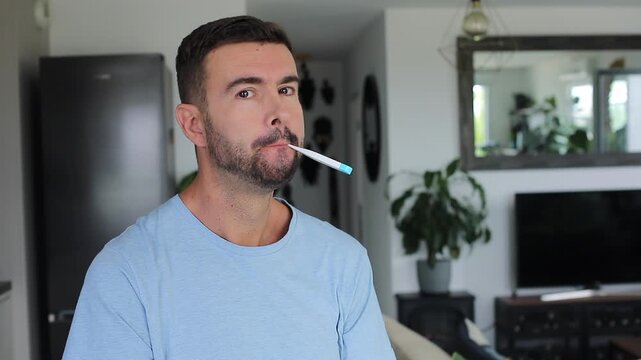 Man checking electronic mouth thermometer and smiling 