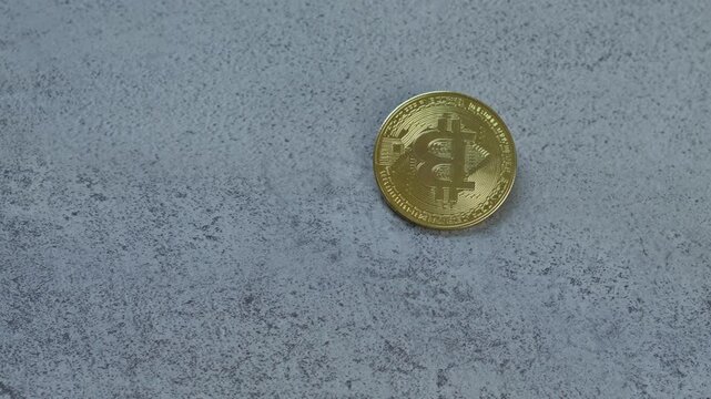 Hand holds and turns shiny gold bitcoin coin for display digital currency details