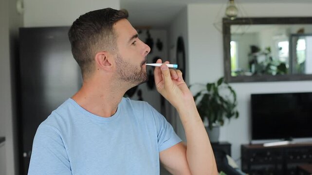 Man checking electronic mouth thermometer and smiling 