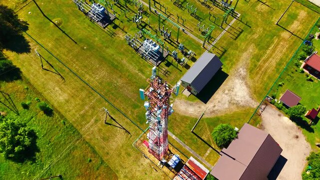 Drone descends toward a telecom tower beside electrical substation in Garkalne