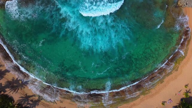 A cinematic drone perspective follows the white foam surging through the narrow rocky opening of Mar Chiquita Beach.