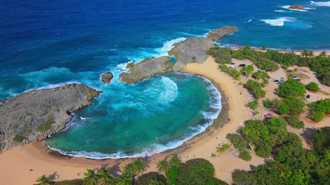 A sweeping drone view captures the famous limestone crescent cove and turquoise waters of Mar Chiquita Beach, Puerto Rico.