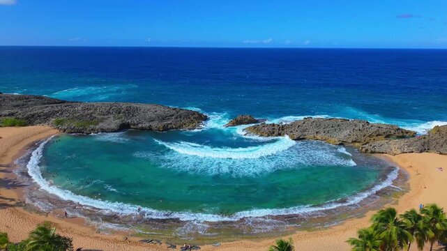 From high above, a drone frames the deep azure ocean blending into the bright turquoise pool at Mar Chiquita, Puerto Rico.