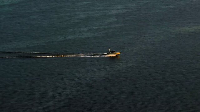 Telephoto drone shot of motorboat cruising in Hanko Archipelago, sunset in Finland