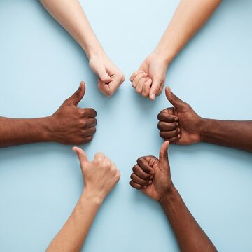 Diverse hands forming a circle with thumbs up and fists on a light blue background, symbolizing unity and agreement.