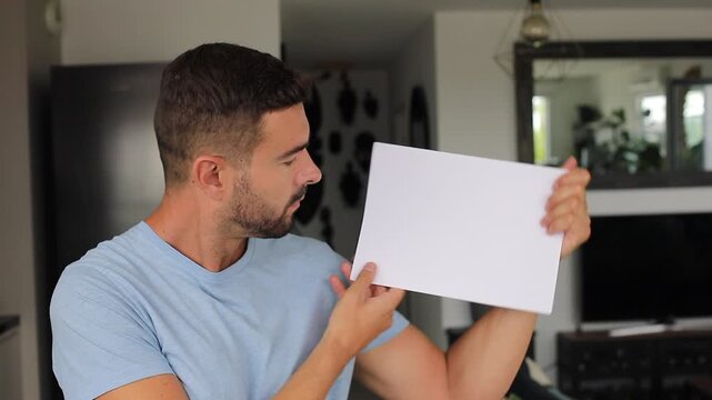 Smiling man holding up blank white paper for custom mockup message