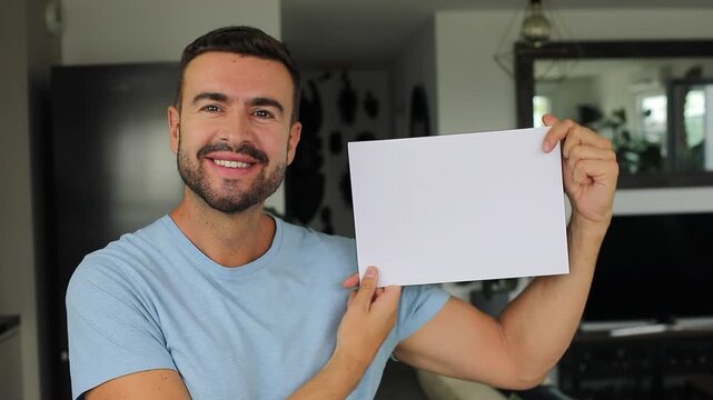 Smiling man holding up blank white paper for custom mockup message