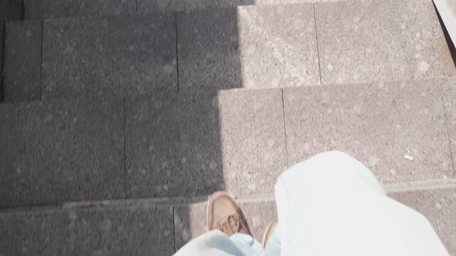 POV view of a person walking down stone stairs outdoors in the city