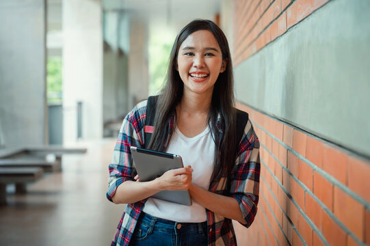 Smiling student stands near brick wall
