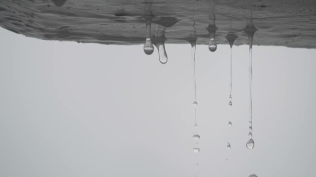 Water dripping from concrete roof edge during heavy rain macro slow motion close up