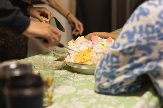 Hands serving a slice of birthday cake at family gathering