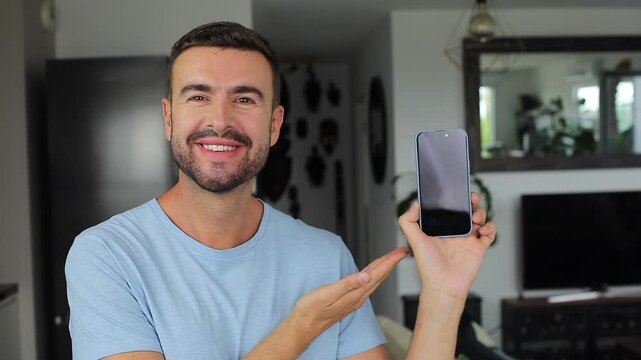 Handsome man showing modern smartphone screen directly on camera 