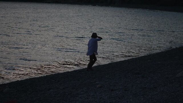 Woman beach ocean silhouette dancing joyfully at twilight by the water's edge feeling carefree
