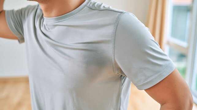 Man experiencing excessive underarm sweating, showing wet armpit stain on a gray athletic t shirt