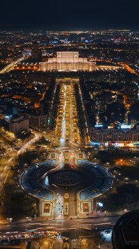 Aerial view of Palace of Parliament in Bucharest Romania at night featuring illuminated boulevards and heavy city traffic.