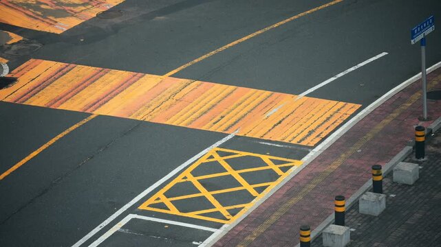 Yellow pedestrian crosswalk and road markings on wet asphalt in a city street, likely in China &mdash;