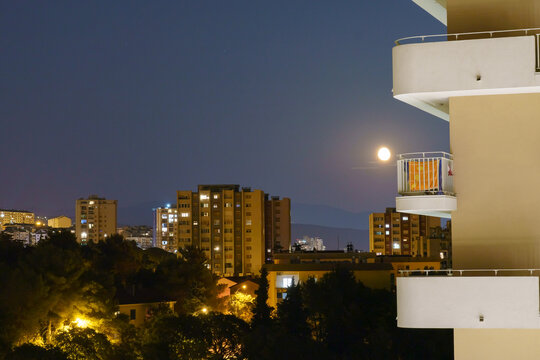 Night cityscape with full moon above apartment buildings