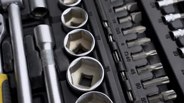 Top view close-up of rotating open toolbox with complete set of socket wrenches, ratchets, and drive bits