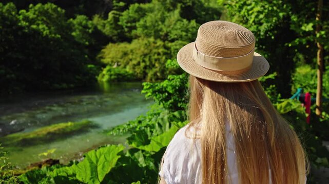 Blonde woman in straw hat at Blue Eye spring in Albania