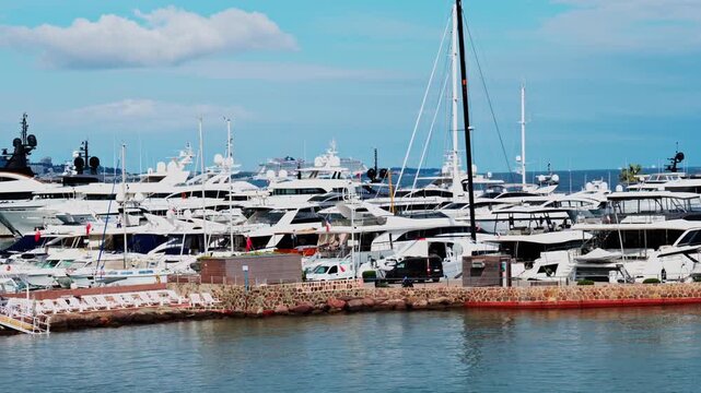 Panoramic view of luxurious yachts docked in a serene harbor during bright summer day.