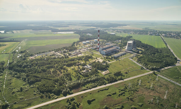 Aerial view of a power plant with a tall chimney and cooling towers surrounded by green fields and forests in Gomel, Gomel Region, Belarus.