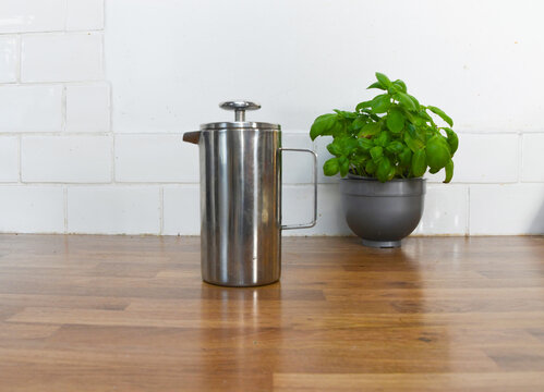 Kitchen Counter with Basil Plant, Wooden Coffee Pots, Cup and Saucer with Copy Space
