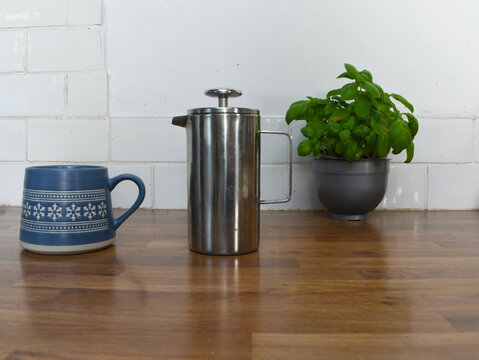 Kitchen Counter with Basil Plant, Wooden Coffee Pots, Cup and Saucer with Copy Space
