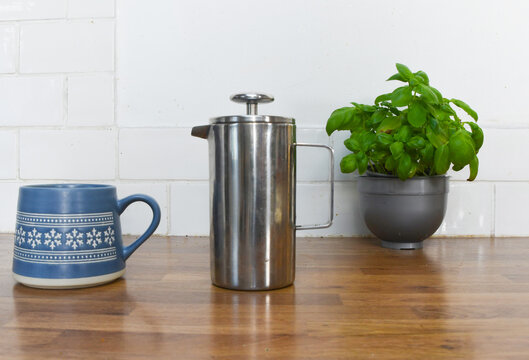 Kitchen Counter with Basil Plant, Wooden Coffee Pots, Cup and Saucer with Copy Space
