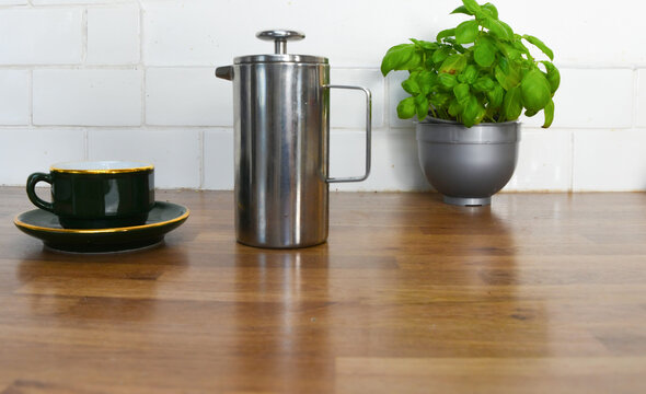 Kitchen Counter with Basil Plant, Wooden Coffee Pots, Cup and Saucer with Copy Space
