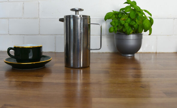 Kitchen Counter with Basil Plant, Wooden Coffee Pots, Cup and Saucer with Copy Space
