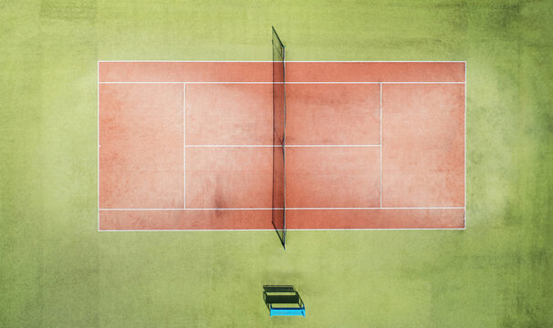 Aerial view of a red clay tennis court with a net surrounded by green grounds in Mogilev, Mogilev Region, Belarus.