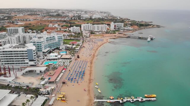 Aerial view of luxury resorts and sandy beach with turquoise water in Cyprus during sunrise.