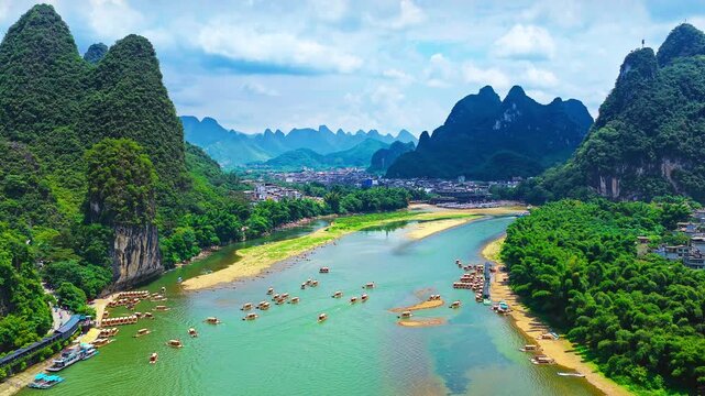 Li River near Guilin, Guangxi, China, flowing through limestone karst peaks and riverside villages with tour boats under a bright blue sky, ideal for travel and tourism campaigns.