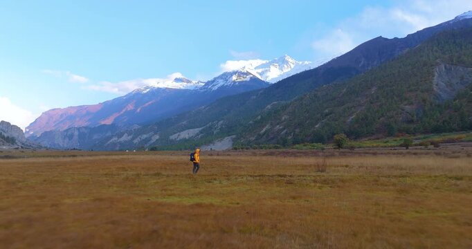 Annapurna Circuit, Manang Nepal, drone passes through an open mountain field following a trekker toward alpine slopes.