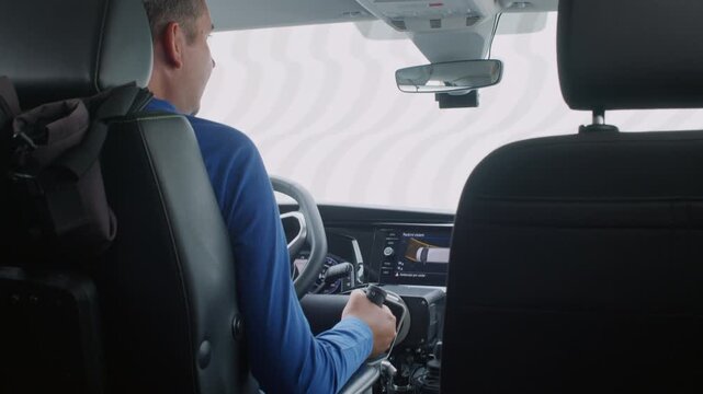 Rear view of a driver with disability operating hand controls and assistive technology in an adapted van for independent transportation.