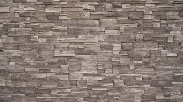 Closeup of stacked stone wall featuring layered rectangular stones in muted gray brown tones. Natural texture subtle lighting create depth