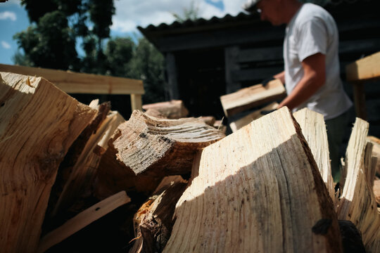 Man stacking chopped firewood into wooden crate outdoors in backyard