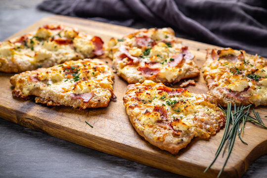 Homemade Flammkuchen with ham, pineapple, and cream cheese on a wooden board