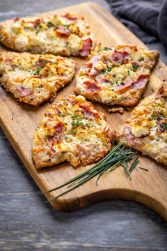 Homemade Flammkuchen with ham, pineapple, and cream cheese on a wooden board