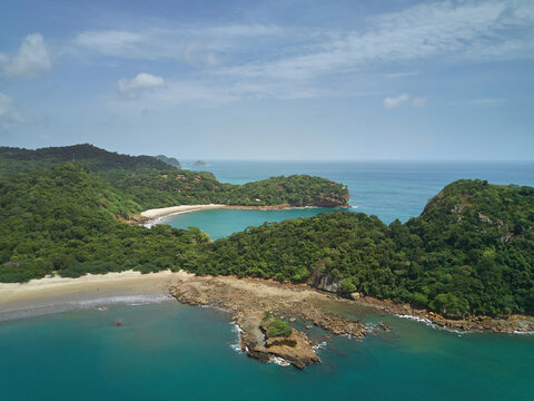 Aerial view of Playa La Redonda featuring a secluded sandy beach, lush green coastal hills, rocky outcrops, and turquoise waters in Tola, Rivas, Nicaragua.