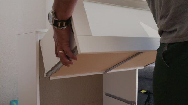 Man installing a drawer into a new white cabinet