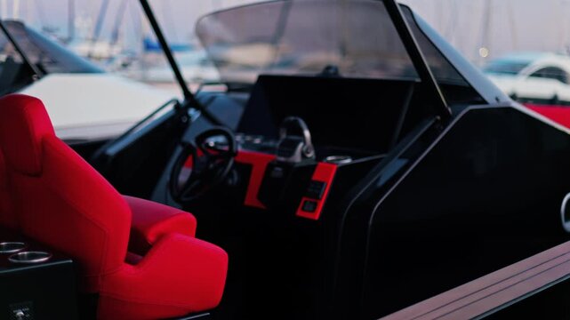 Luxury yacht helm with red seats and modern dashboard parked at marina.