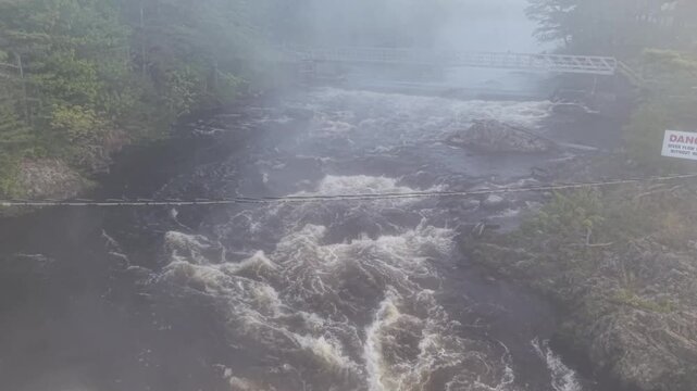 Moving upstream over foot bridge on a cold and foggy spring morning in Old Town, Maine 