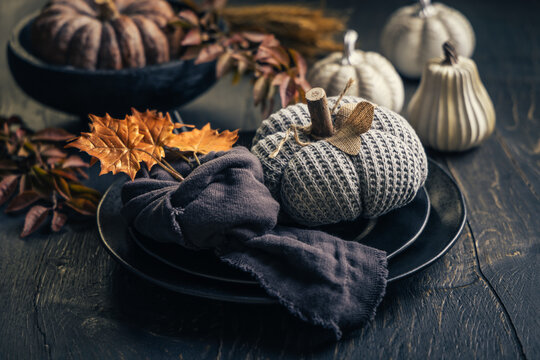 Cozy autumn table setting with knitted pumpkins and fall leaves